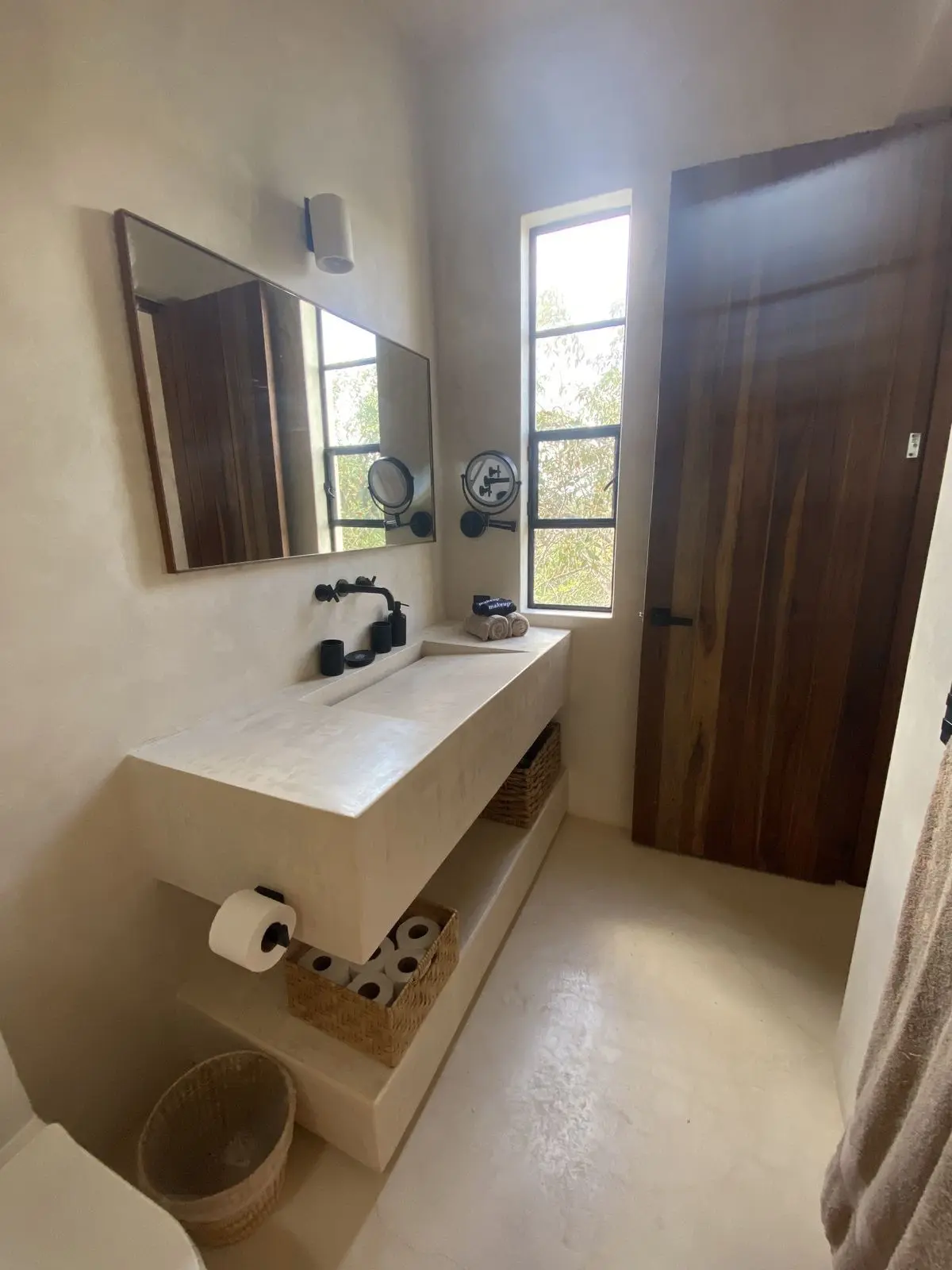 Bathroom with a microcement vanity and wooden door after a full renovation in Marbella